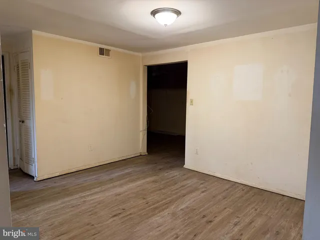 a view of an empty room with wooden floor and closet