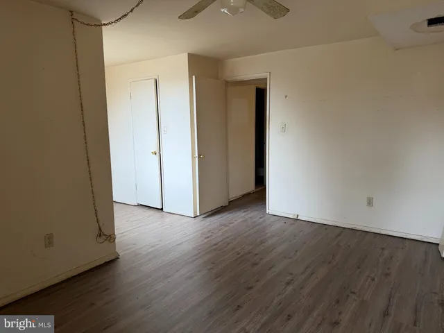 a view of an empty room with wooden floor and closet