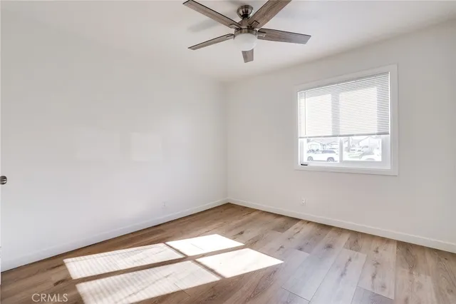 an empty room with wooden floor fan and windows