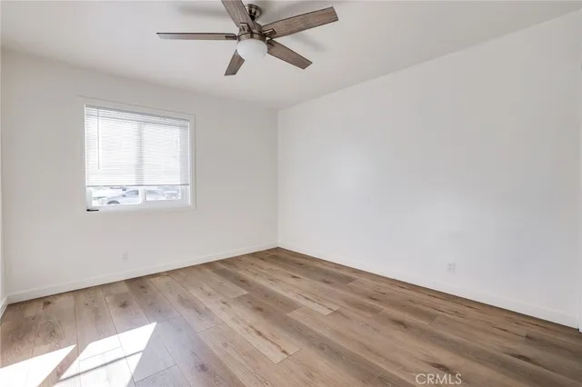 an empty room with wooden floor fan and windows
