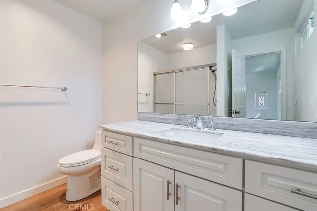 a bathroom with a granite countertop toilet a sink and a mirror