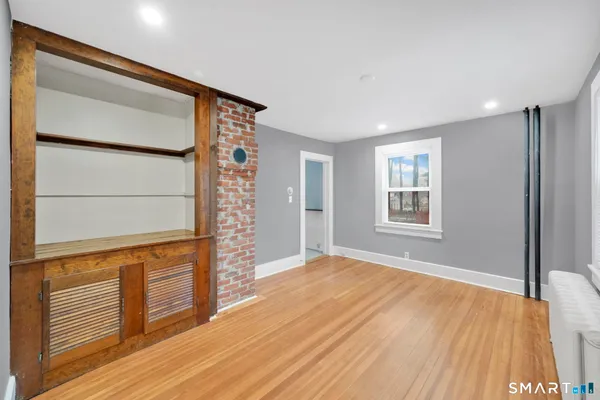 a view of an empty room with wooden floor and a window