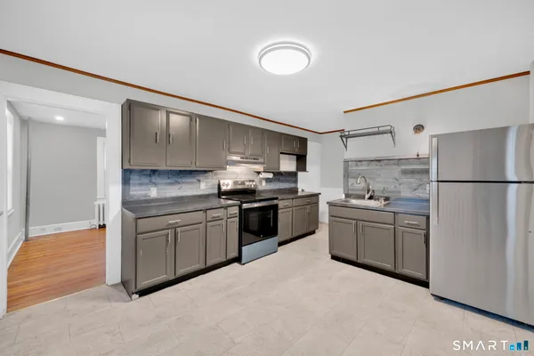 a kitchen with granite countertop a refrigerator stove top oven and sink