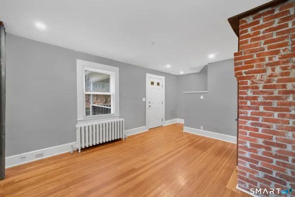 a view of an empty room with wooden floor and a window