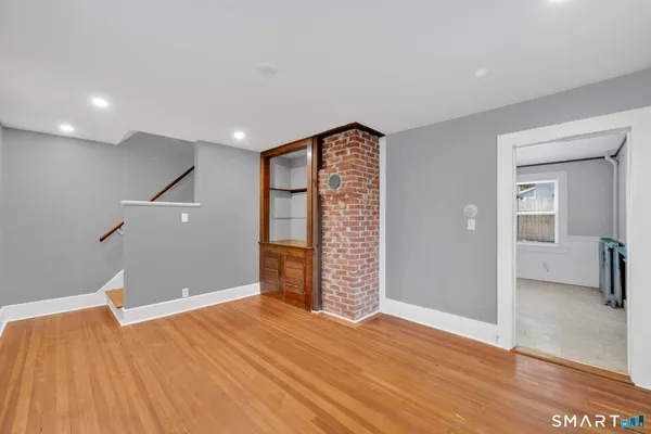 a view of an empty room with wooden floor and closet