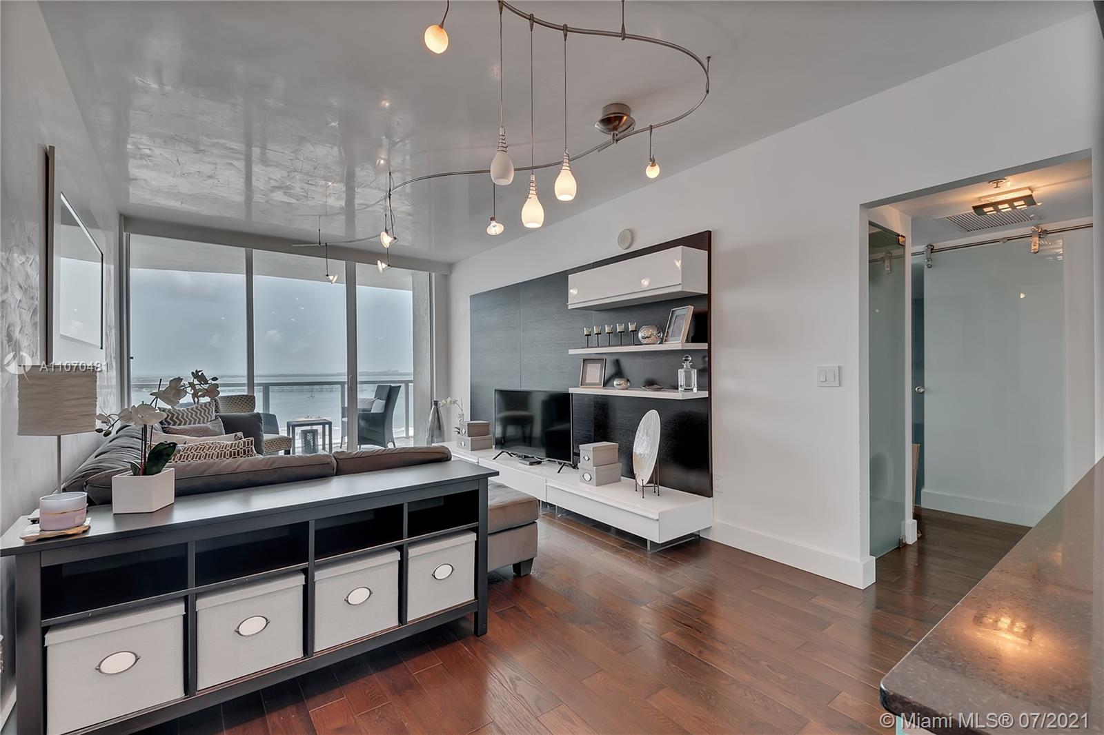 a view of a room with kitchen island stainless steel appliances wooden floor and window