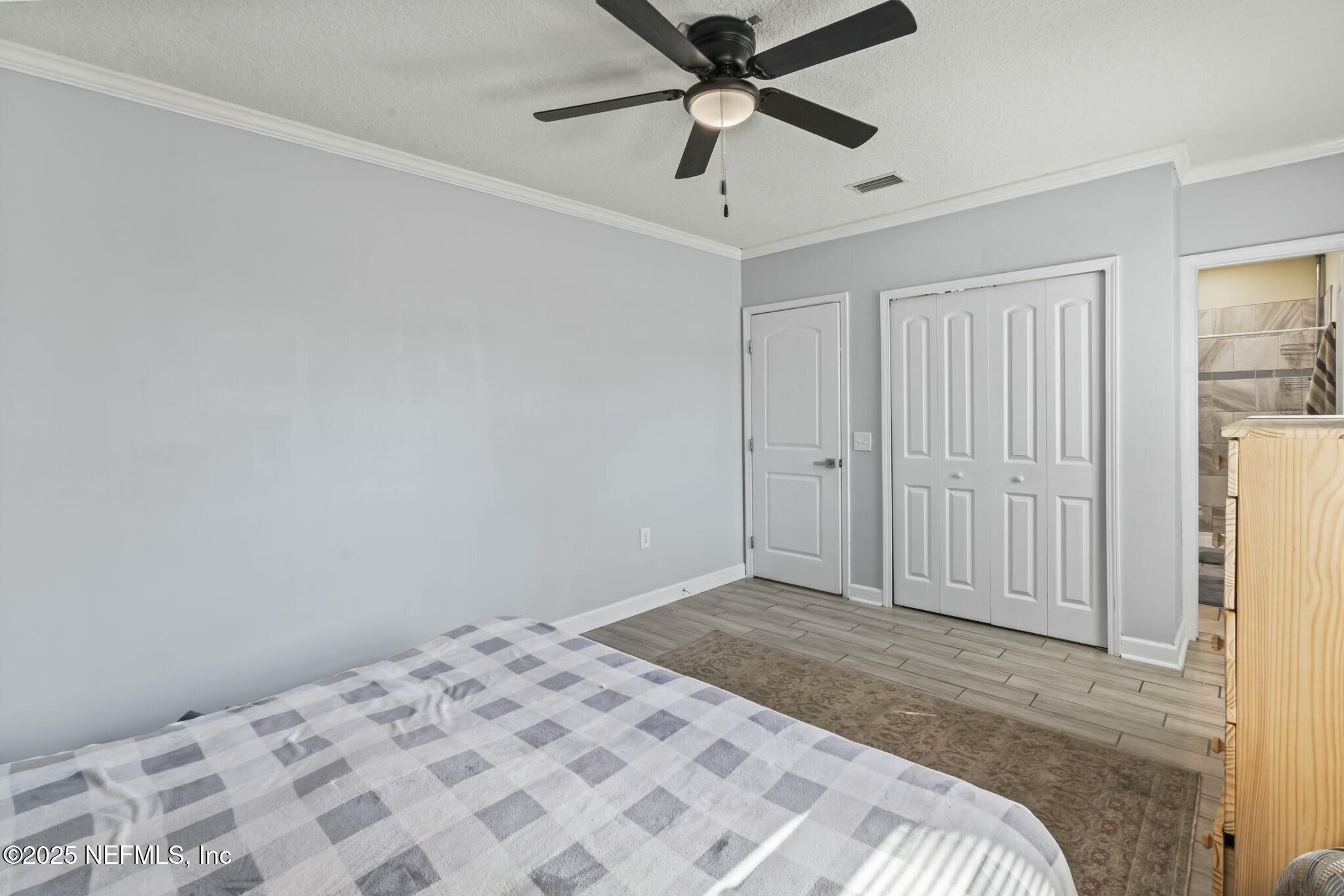6053 Firestone Road Jacksonville, FL 32244 - Photo 13 of 34 a bedroom with a bed and a chandelier fan