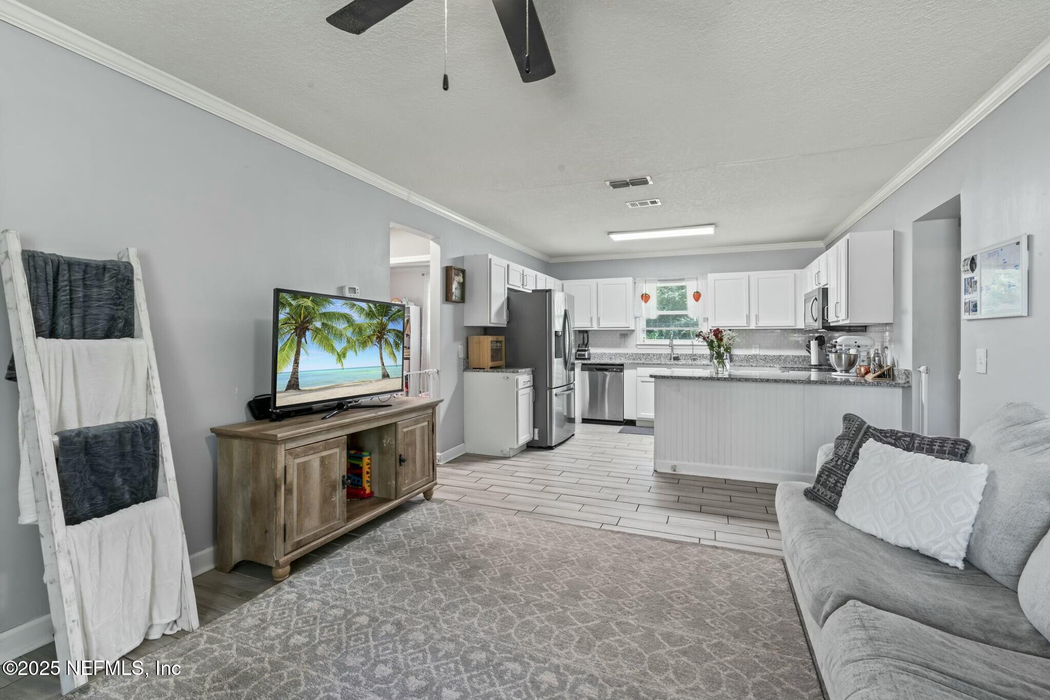 6053 Firestone Road Jacksonville, FL 32244 - Photo 3 of 34 a living room with furniture and a flat screen tv
