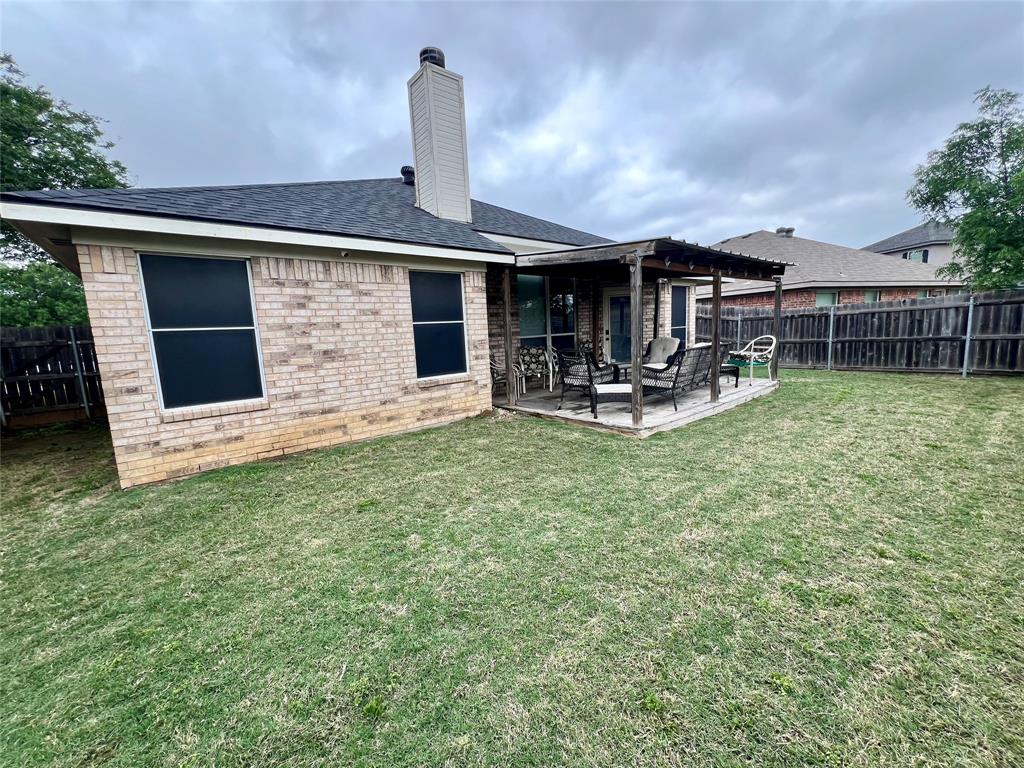 12201 Rolling Ridge Drive Fort Worth, TX 76028 - Photo 21 of 21 Expansive backyard featuring a covered patio, brick exterior, and a prominent chimney