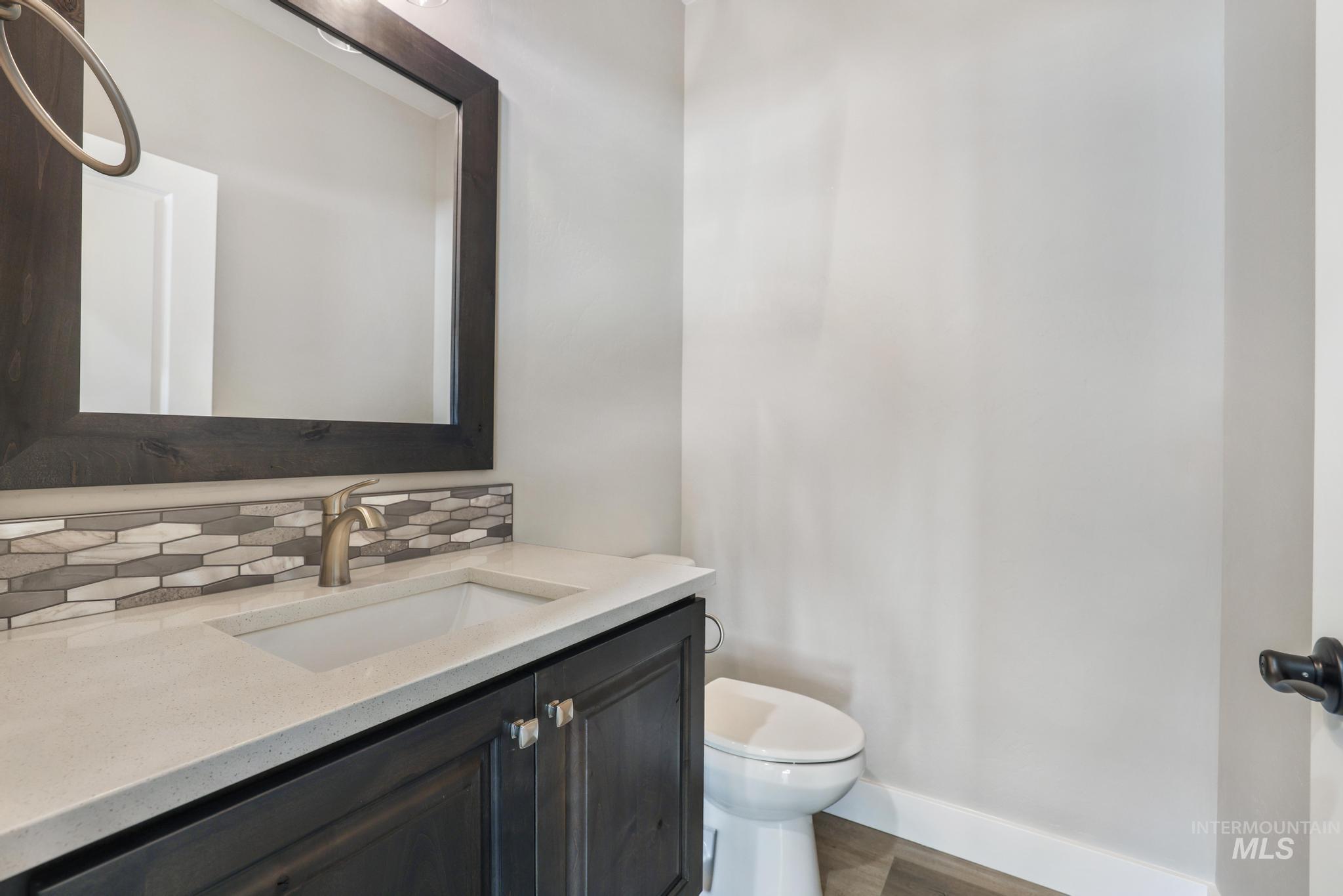 298 Sandi Road Twin Falls, ID 83301 - Photo 12 of 24 Bathroom featuring a dark wood-finish vanity with a light countertop, an integrated sink, a rectangular framed mirror, and a decorative tile backsplash
