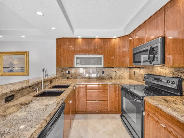 a kitchen with stainless steel appliances granite countertop sink stove top oven and cabinets