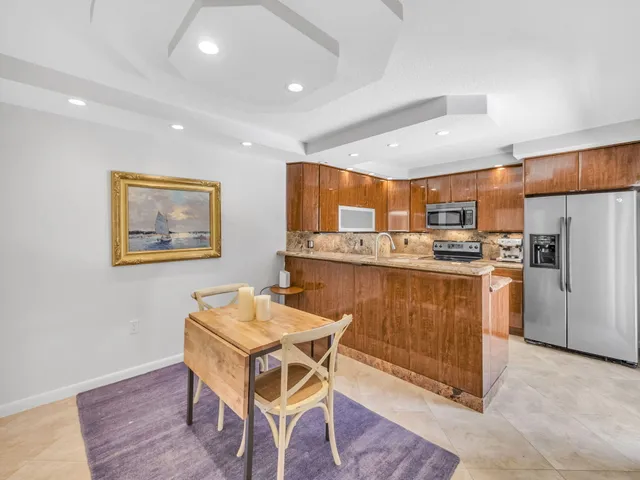 a kitchen with stainless steel appliances granite countertop a stove a sink a refrigerator and a dining table with wooden floor