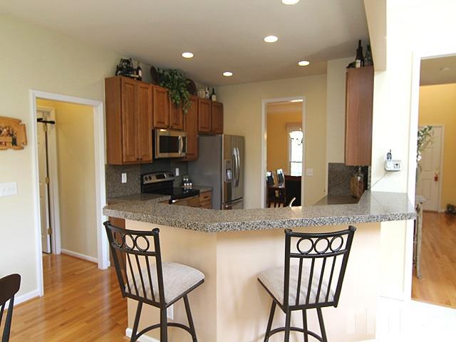 1505 Autumn Ridge Drive Durham, NC 27712 - Photo 4 of 25 a kitchen with stainless steel appliances granite countertop a table chairs and a refrigerator