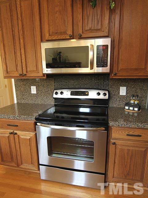1505 Autumn Ridge Drive Durham, NC 27712 - Photo 6 of 25 a stove top oven sitting inside of a kitchen with granite countertop wooden cabinets