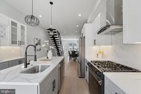 a kitchen with kitchen island granite countertop a sink a stove and a wooden floors
