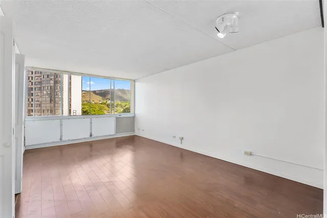 a view of an empty room with a window and wooden floor
