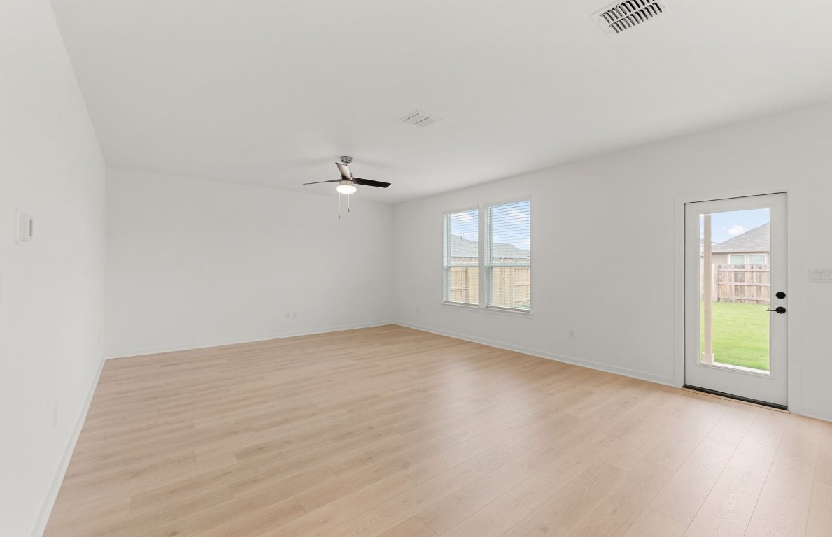 360 Begonia Street Buda, TX 78610 - Photo 10 of 26 an empty room with windows and chandelier fan