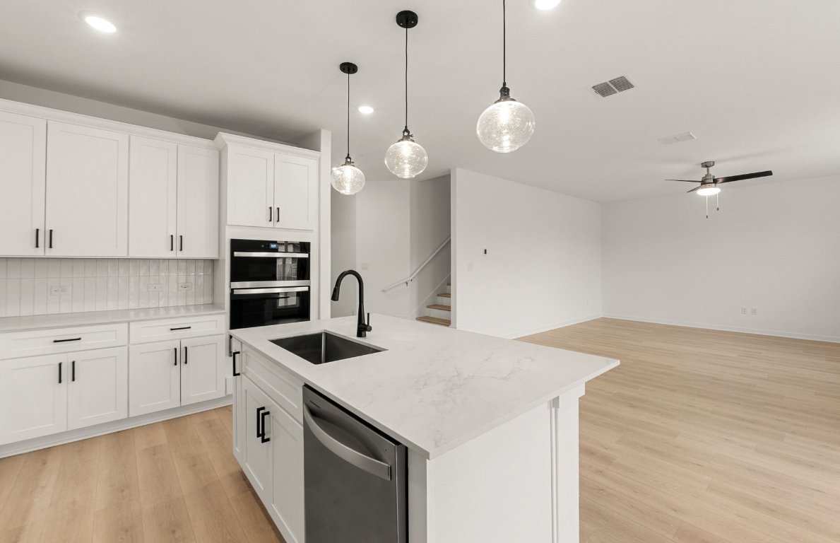 360 Begonia Street Buda, TX 78610 - Photo 6 of 26 a kitchen that has a lot of cabinets and wooden floor