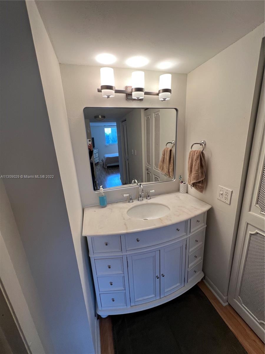 1665 Bay Road, Unit 517 Miami Beach, FL 33139 - Photo 18 of 26 a bathroom with a granite countertop sink a mirror and vanity