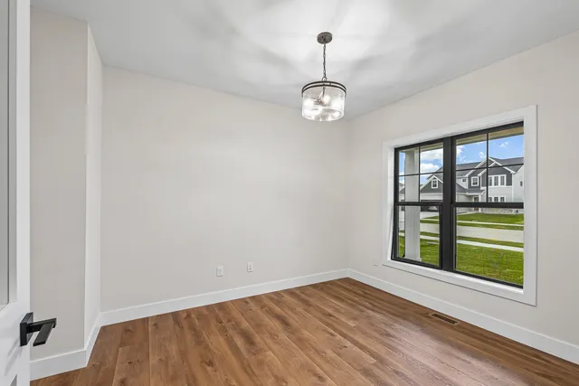 a view of empty room with wooden floor and window