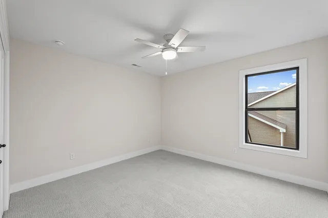an empty room with a window and ceiling fan