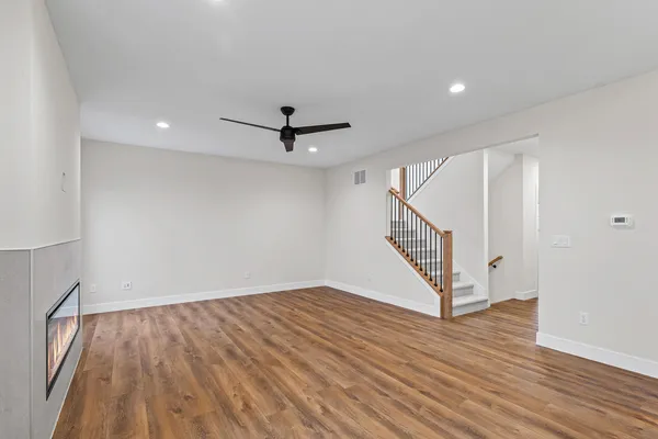 a view of an empty room with wooden floor and stairs