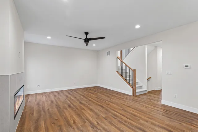 a view of an empty room with wooden floor and stairs
