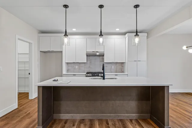 a large kitchen with kitchen island a counter space a sink stainless steel appliances and cabinets