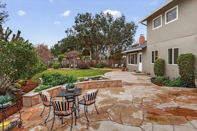 a view of a patio with table and chairs potted plants and large tree