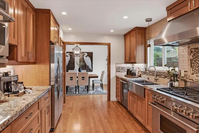a kitchen with stainless steel appliances granite countertop a sink a stove and a refrigerator