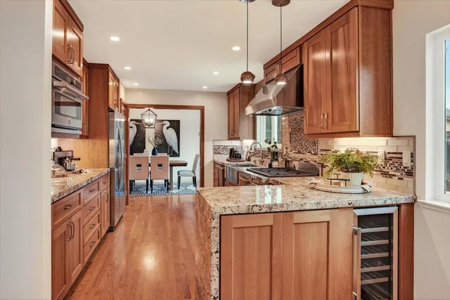 a kitchen with stainless steel appliances granite countertop a stove top oven a sink dishwasher a refrigerator and cabinets with wooden floor