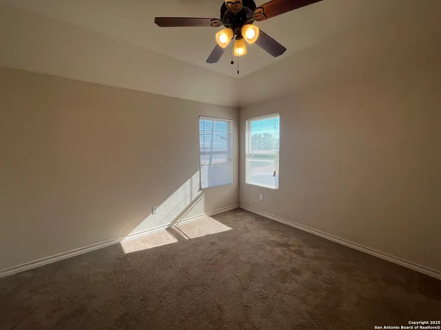 an empty room with windows and chandelier fan