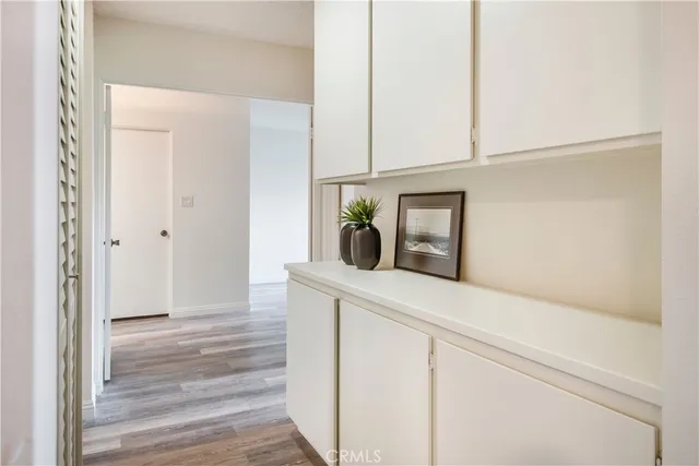 a view of a hallway with wooden floor and cabinet