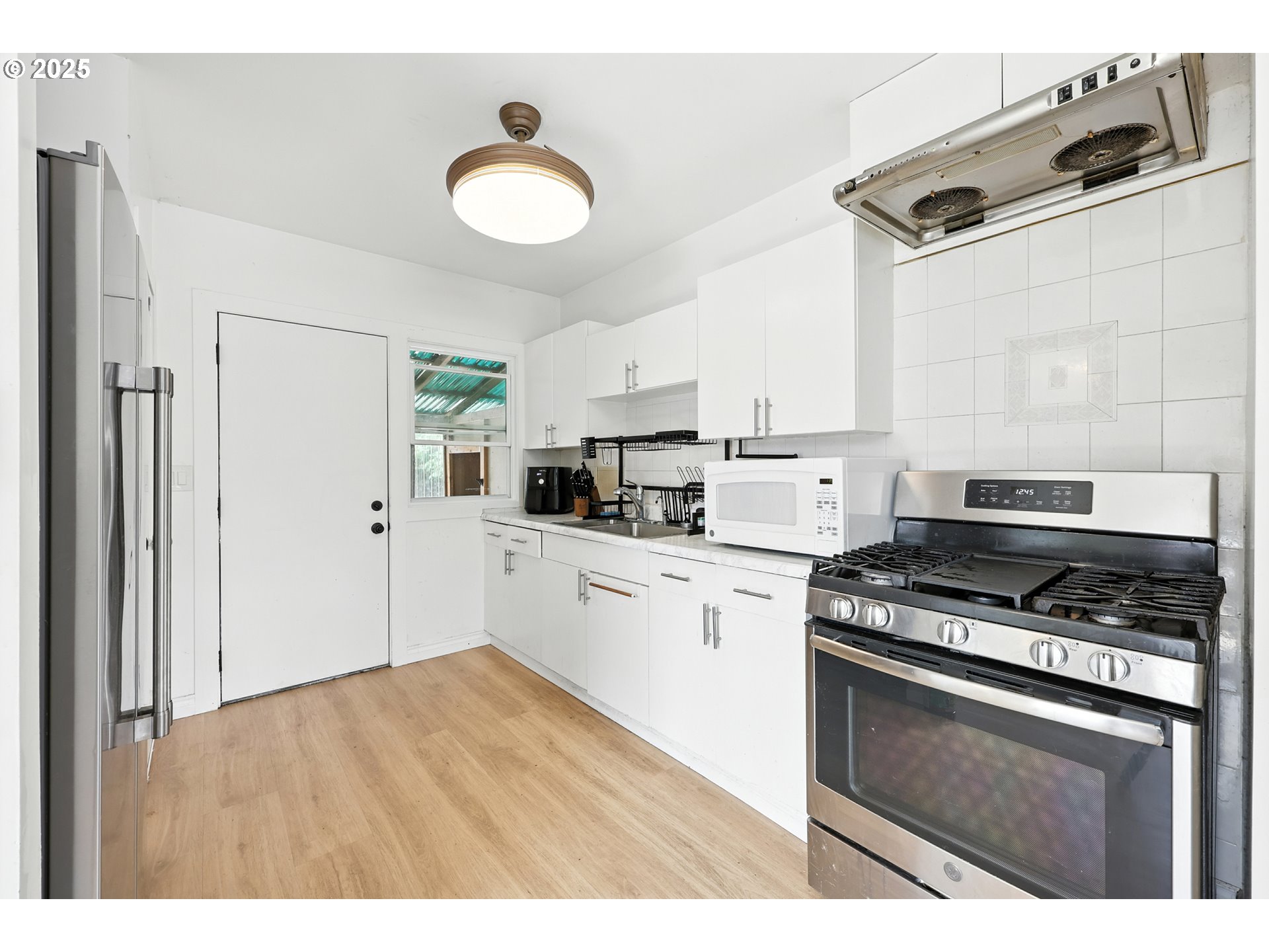 1611 Northeast 102nd Avenue Portland, OR 97220 - Photo 5 of 30 a kitchen with stainless steel appliances granite countertop a stove a sink and white cabinets