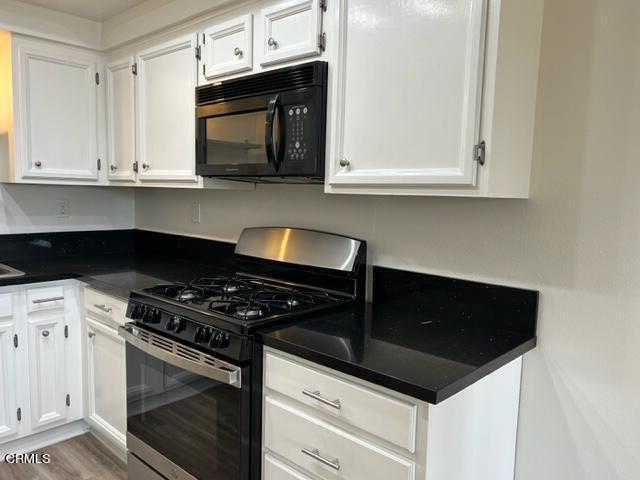 4907 Dunes Street, Unit 7 Oxnard, CA 93035 - Photo 11 of 74 a kitchen with granite countertop white cabinets and black appliances