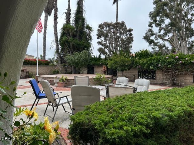 4907 Dunes Street, Unit 7 Oxnard, CA 93035 - Photo 56 of 74 a view of a patio with table and chairs potted plants and a palm tree