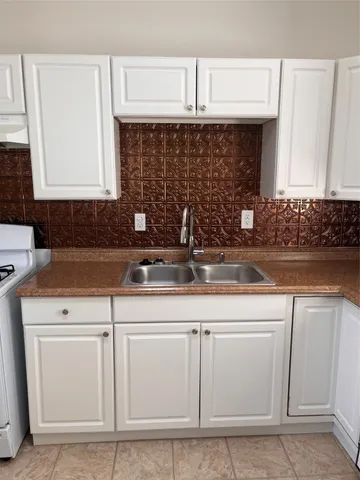 a kitchen with white cabinets and sink