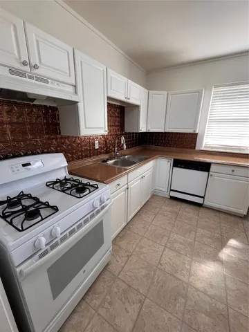 a kitchen with granite countertop a stove sink and cabinets