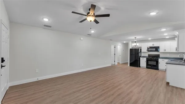 an empty room with wooden floor ceiling fan and windows