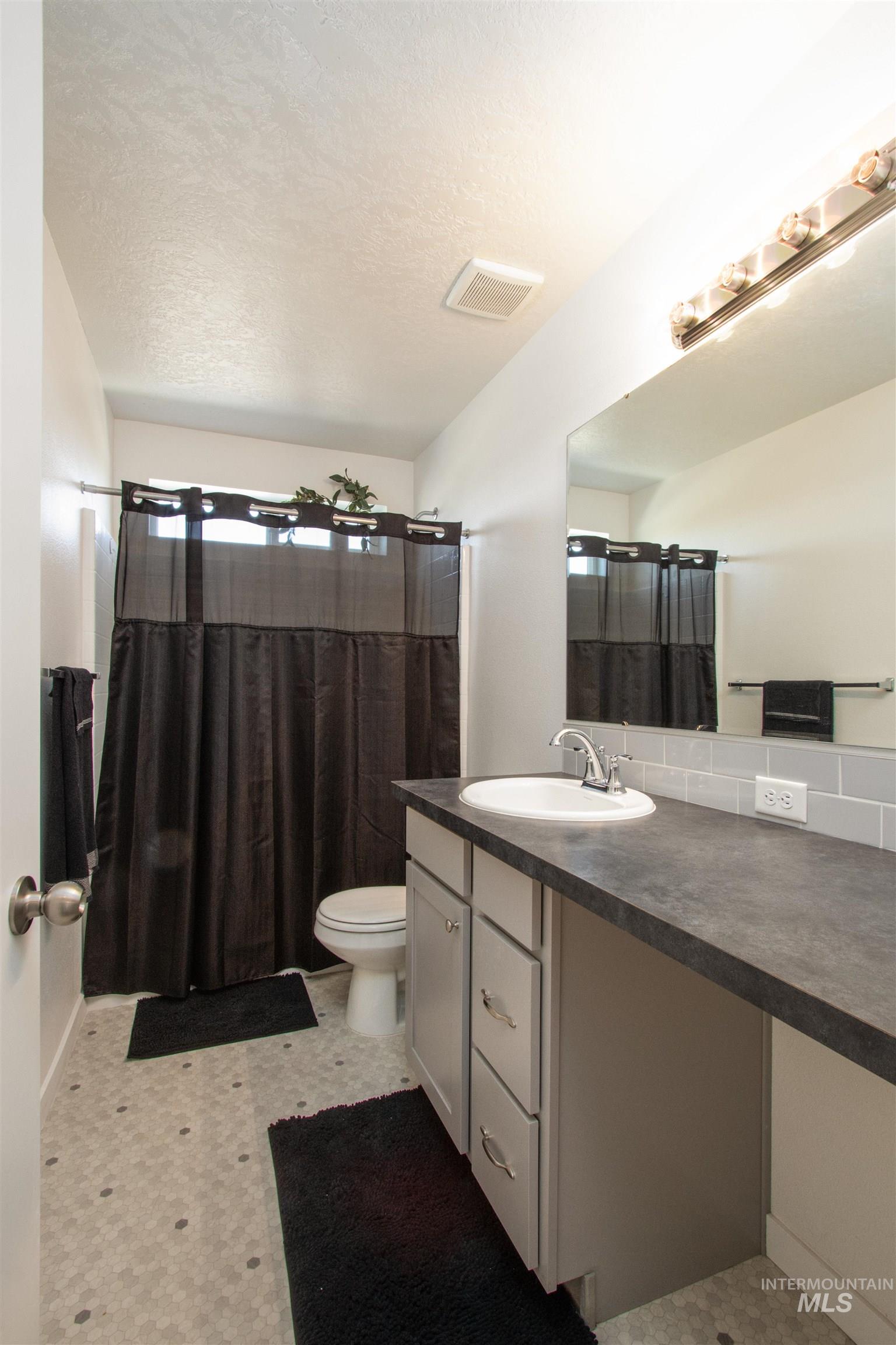 7698 South Seabreeze Way Boise, ID 83709 - Photo 11 of 16 Full bath with vanity, a shower with shower curtain, light flooring, and a textured ceiling