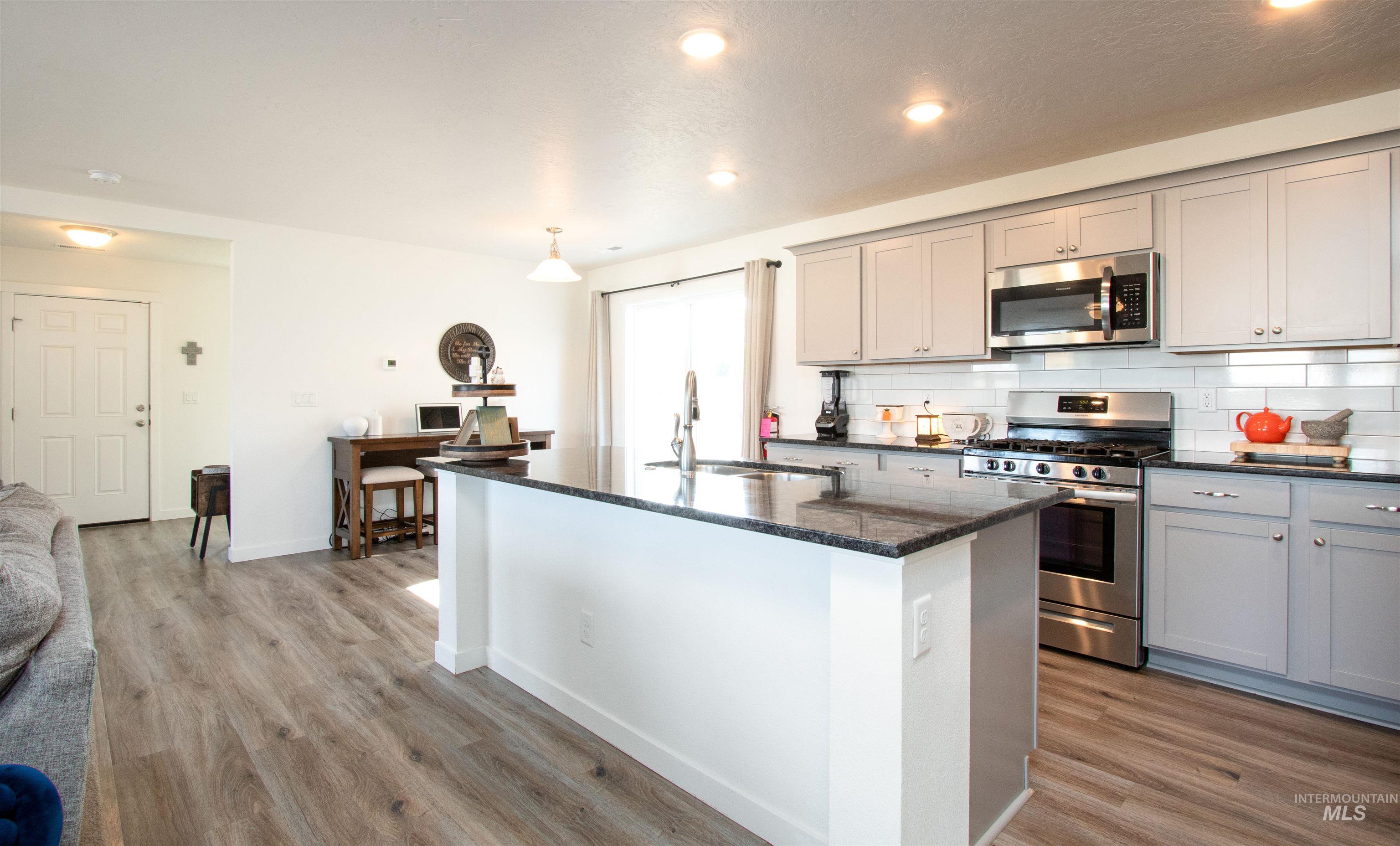7698 South Seabreeze Way Boise, ID 83709 - Photo 4 of 16 Kitchen with stainless steel appliances, gray cabinets, dark stone counters, a kitchen island with sink, and recessed lighting