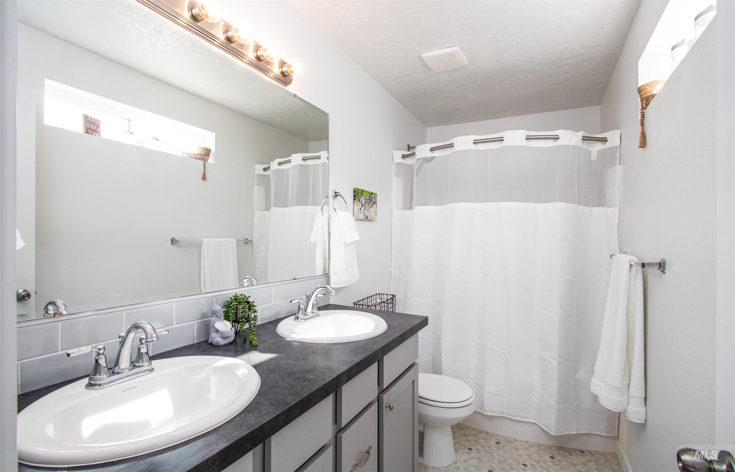 7698 South Seabreeze Way Boise, ID 83709 - Photo 8 of 16 Bathroom featuring double vanity, light tile patterned floors, and shower / tub combo