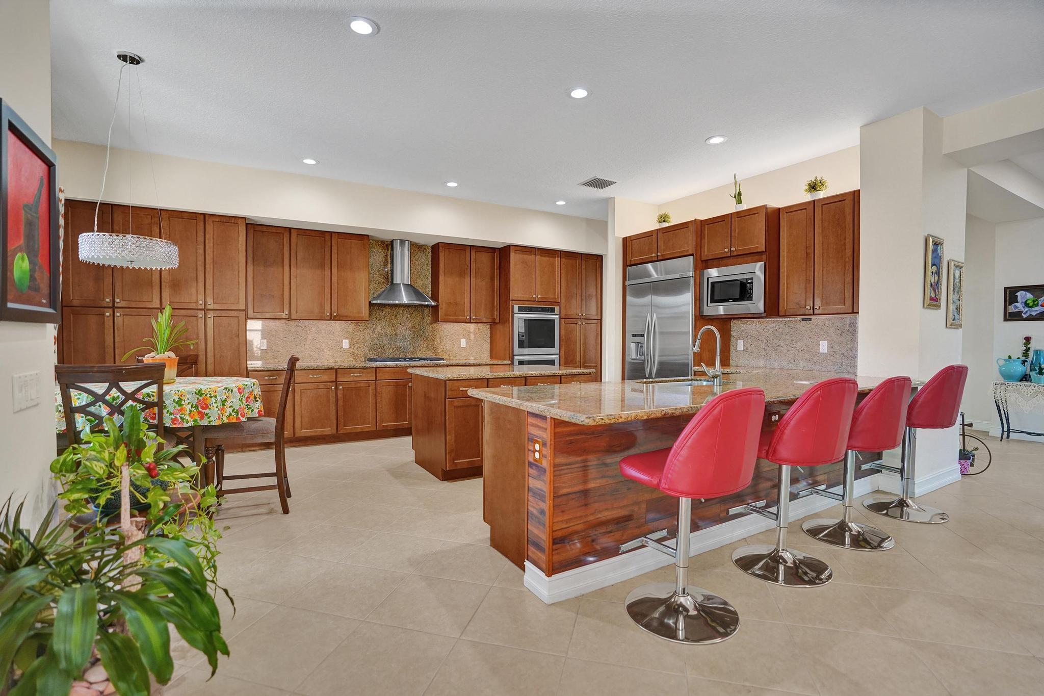 16610 Gateway Bridge Drive Delray Beach, FL 33446 - Photo 5 of 67 a kitchen with stainless steel appliances kitchen island granite countertop a stove a sink a refrigerator and chairs