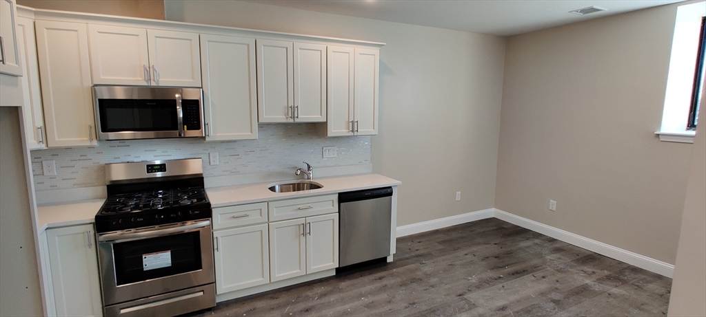 191 North Common Street, Unit 207 Lynn, MA 01905 - Photo 2 of 8 a kitchen with granite countertop white cabinets and black appliances