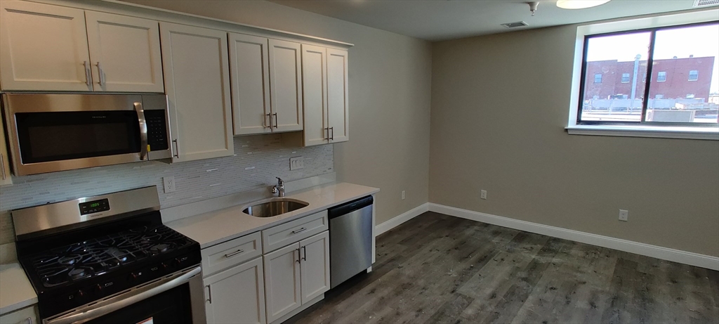 191 North Common Street, Unit 207 Lynn, MA 01905 - Photo 3 of 8 a kitchen with granite countertop white cabinets stainless steel appliances and a sink