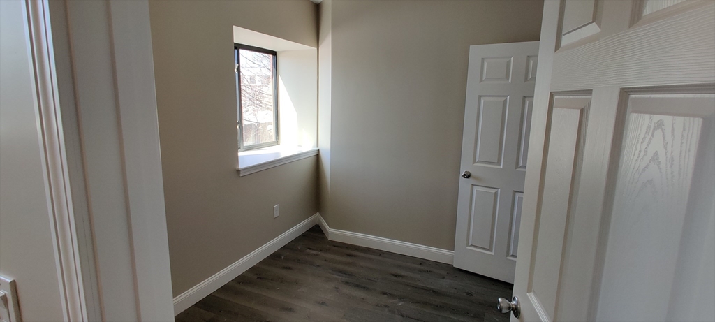 191 North Common Street, Unit 207 Lynn, MA 01905 - Photo 4 of 8 a view of an empty room with wooden floor and a window