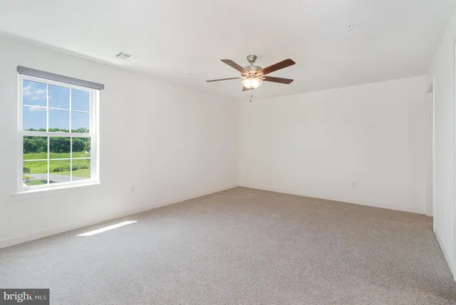 an empty room with a window and a fan