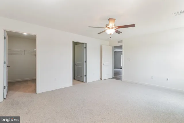 an empty room with closet and a ceiling fan