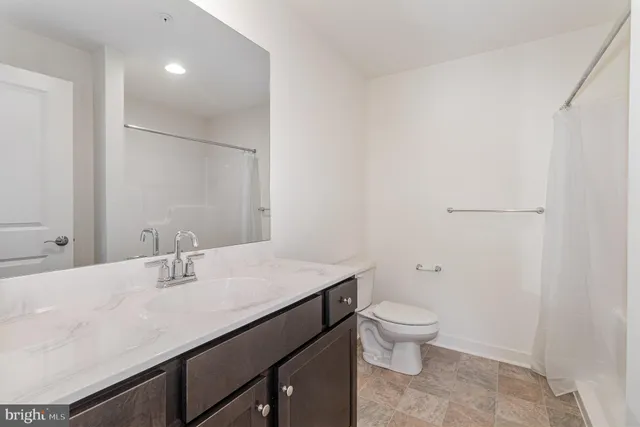 a bathroom with a granite countertop sink a toilet and a mirror