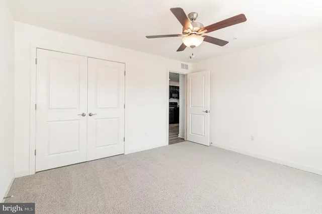 an empty room with ceiling fan and window